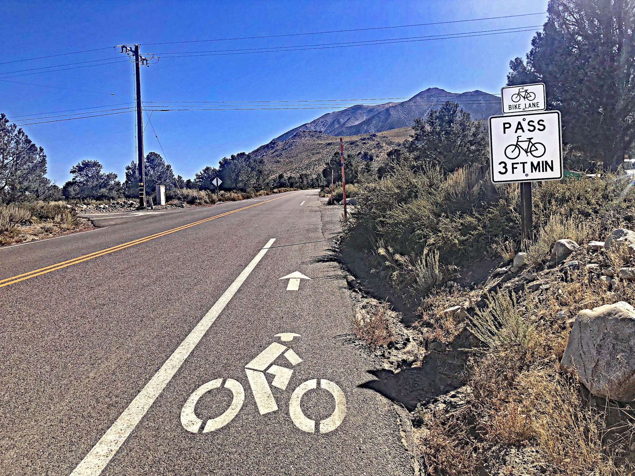 Cyclist approaching share the road sign and road marker on Rock Creek Road