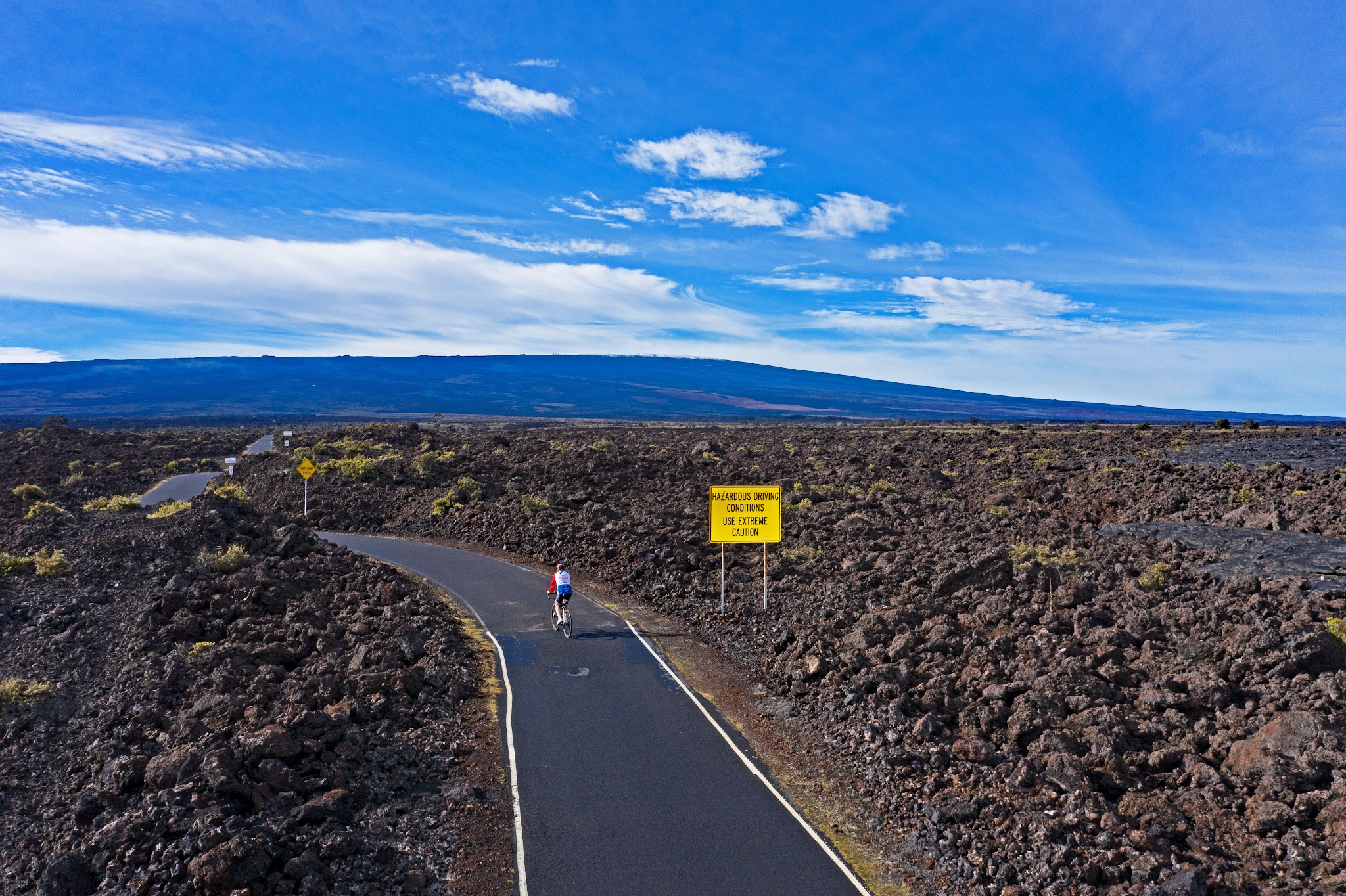 Cycling Mauna Loa Volcano - roadway, lava field and roadway sign