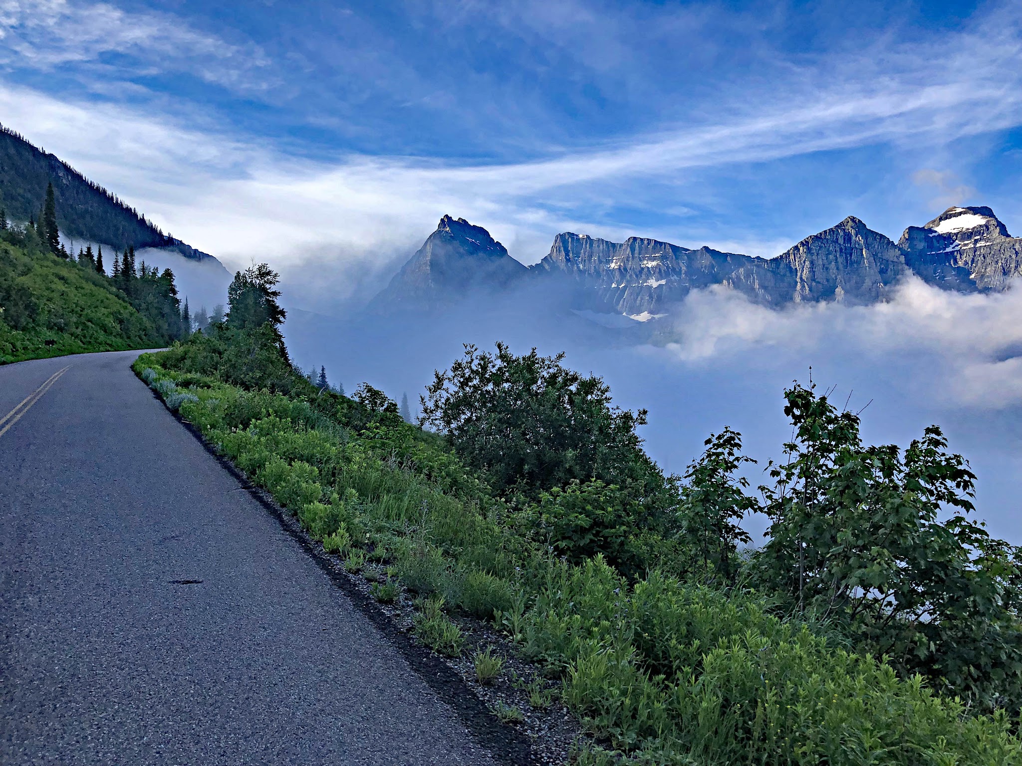 Cycling Logan Pass West, Going-to-the-Sun Road, Glacier National Park - roadside overlooking sharp, steep mountain peaks shrouded in fog