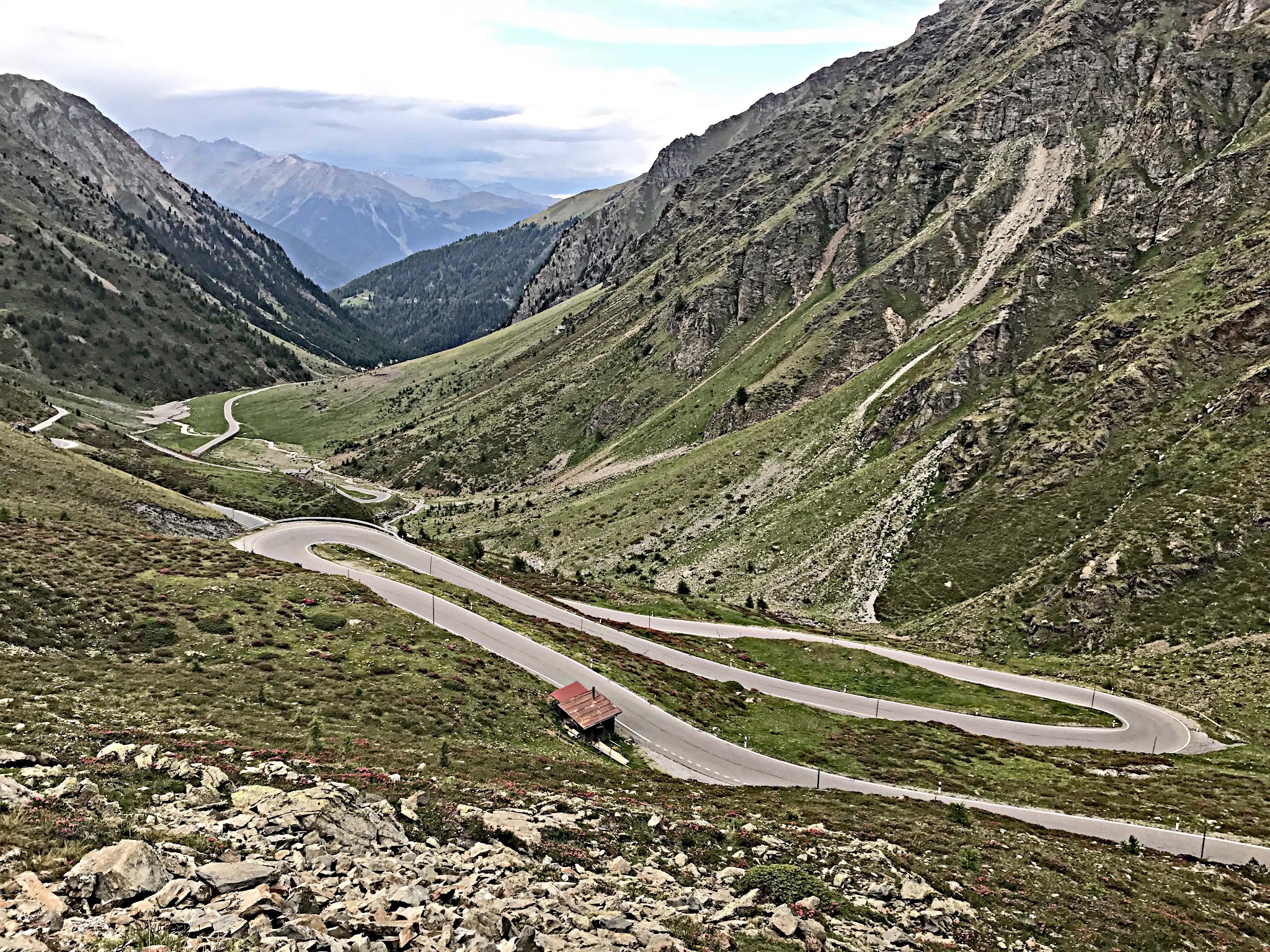 Bicycle climb of Umbrail Pass - hairpins, farmhouse, roadway, mountains