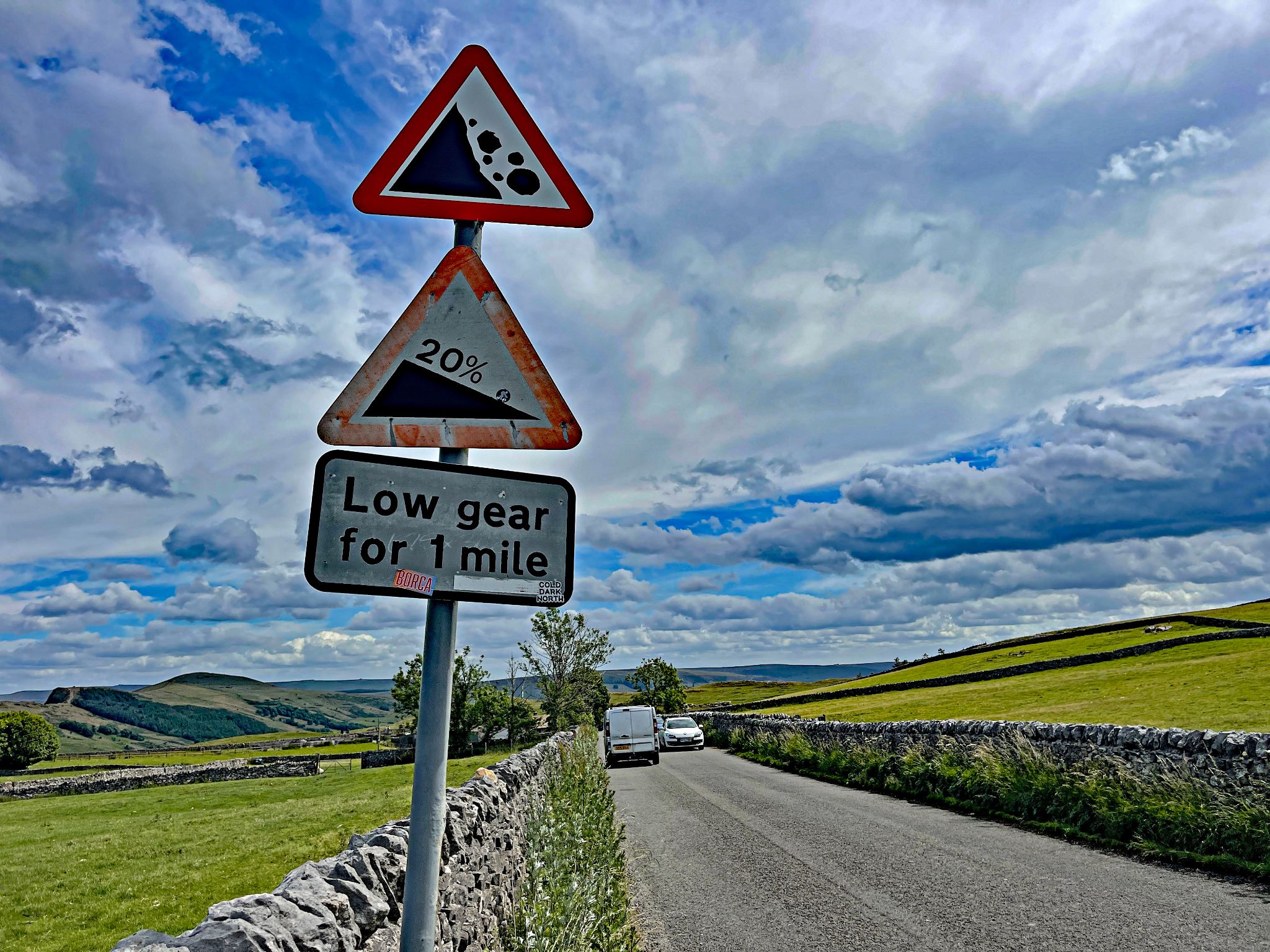 road sign warns of: falling rock, 20% grade, low gear for 1 mile