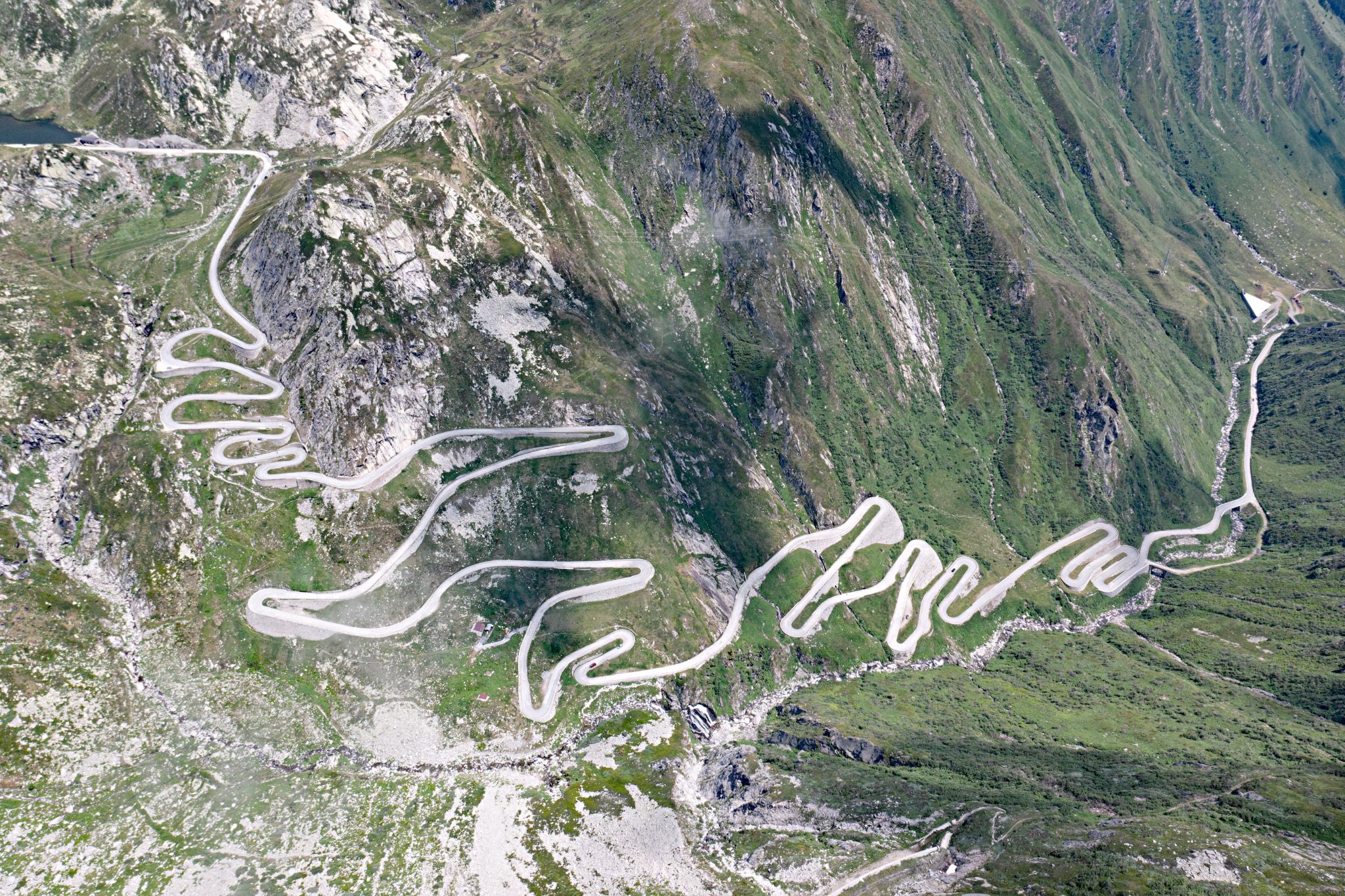 Cycling St. Gotthard Pass, Switzerland  - aerial drone view shows iconic hairpin turns snaking up entire mountainside