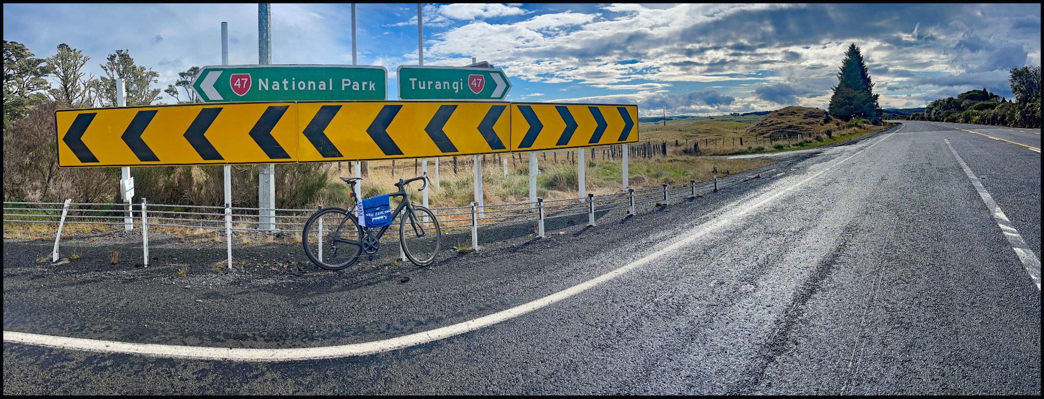 Climbing Ruapehu Ski Area, New Zealand bike parked against yellow road arrow signs next to signs for National Park and Turangi