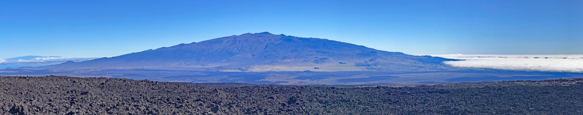panoramic view of Mauna Kea, rising above the fog line, as seen from Mauna Loa