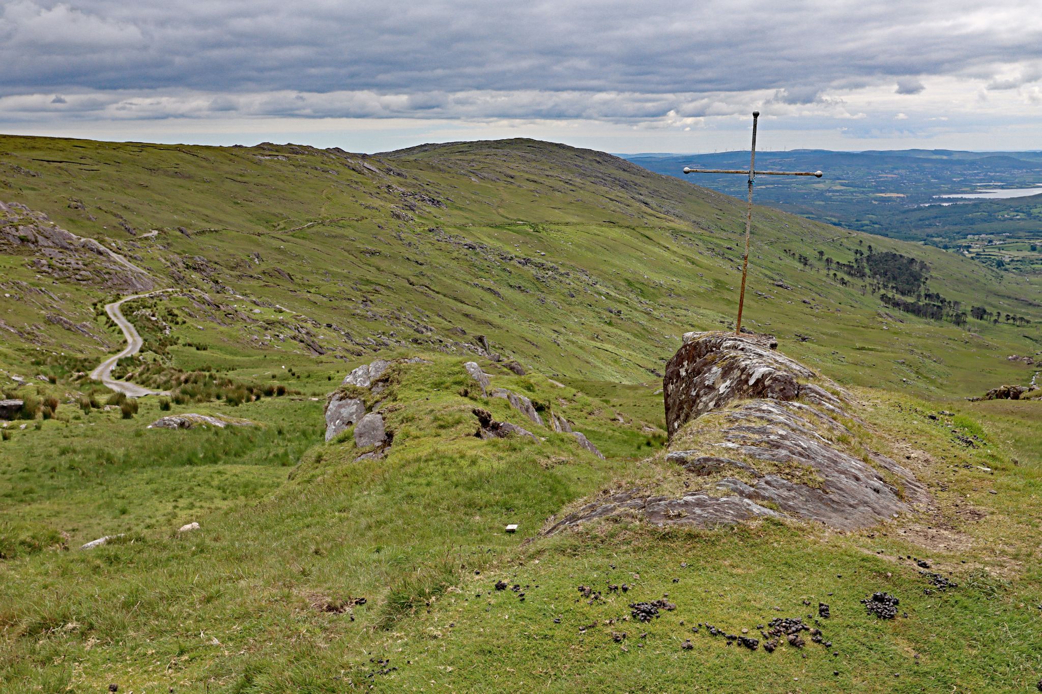 small metal cross atop rock in pastureland