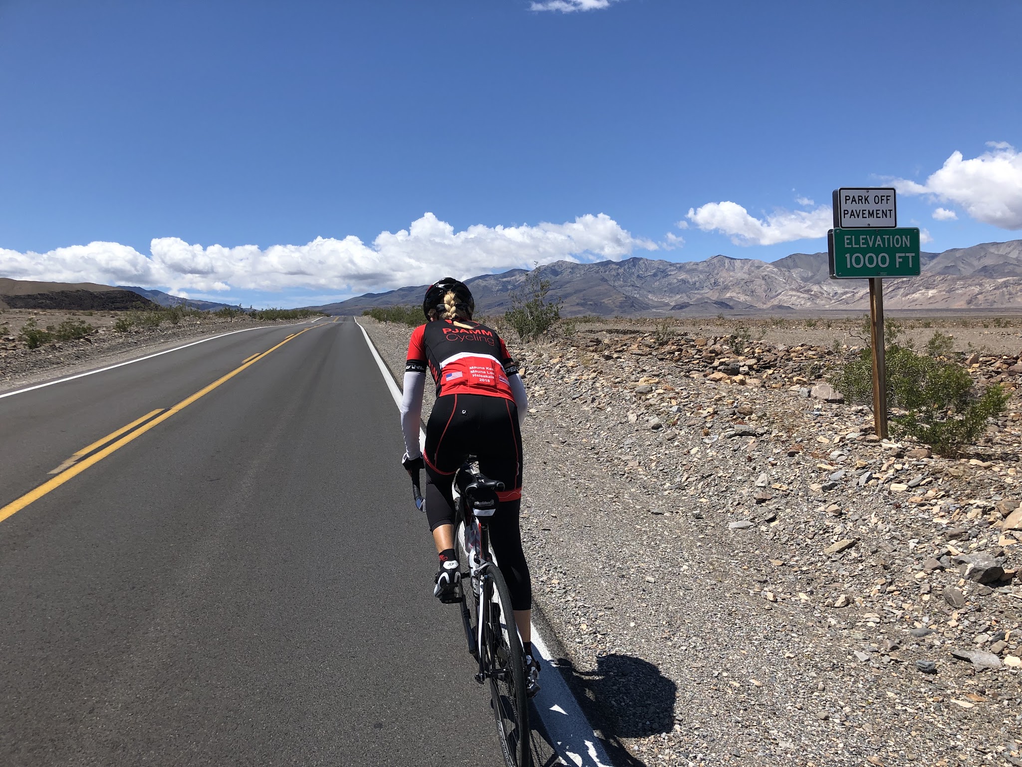 Emigrant Pass, Death Valley National Park Climb Emigrant Pass, Death Valley by bike - cyclist on bike on Hwy 190 passing 1000' elevation sign