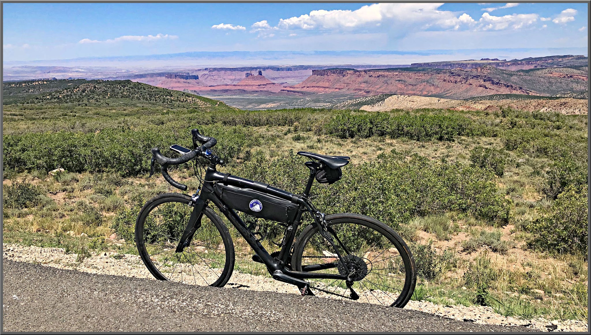 Cycling La Sal Loop Road at Castle Valley - bike parked on side of roadway overlooking scrub brush, and beyond red bluffs and canyons