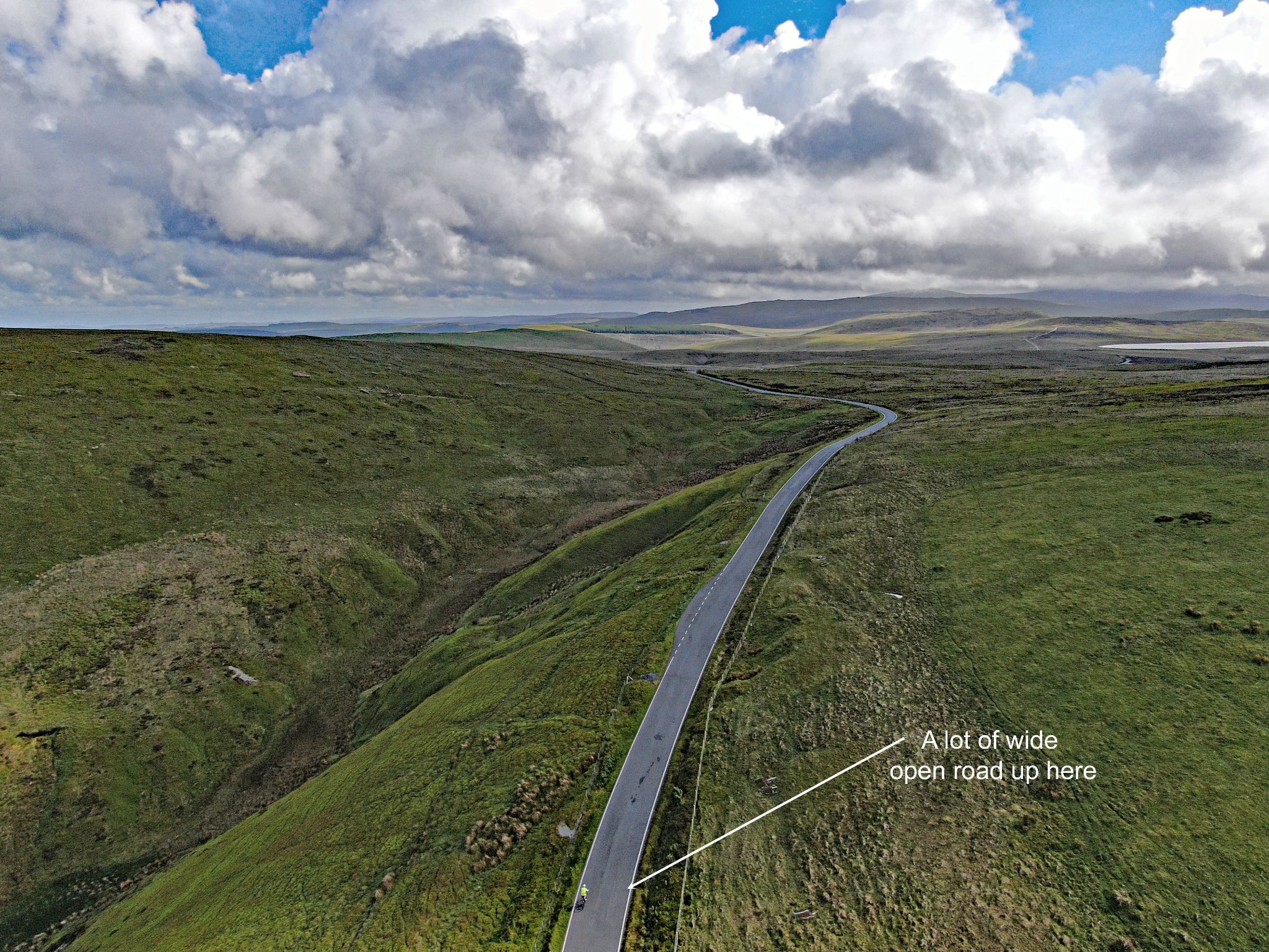 aerial drone view shows PJAMM Cyclist as the only passerby on a long stretch of country road