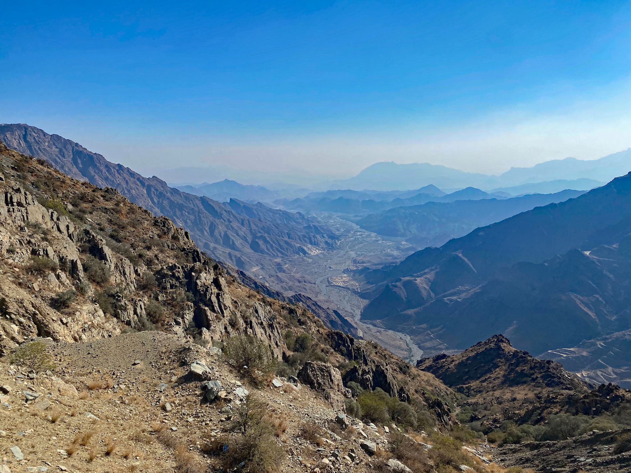 Cycling Al Bahah Pass, Saudi Arabia - canyon views show jagged mountains in distance, scrub brush, blue sky