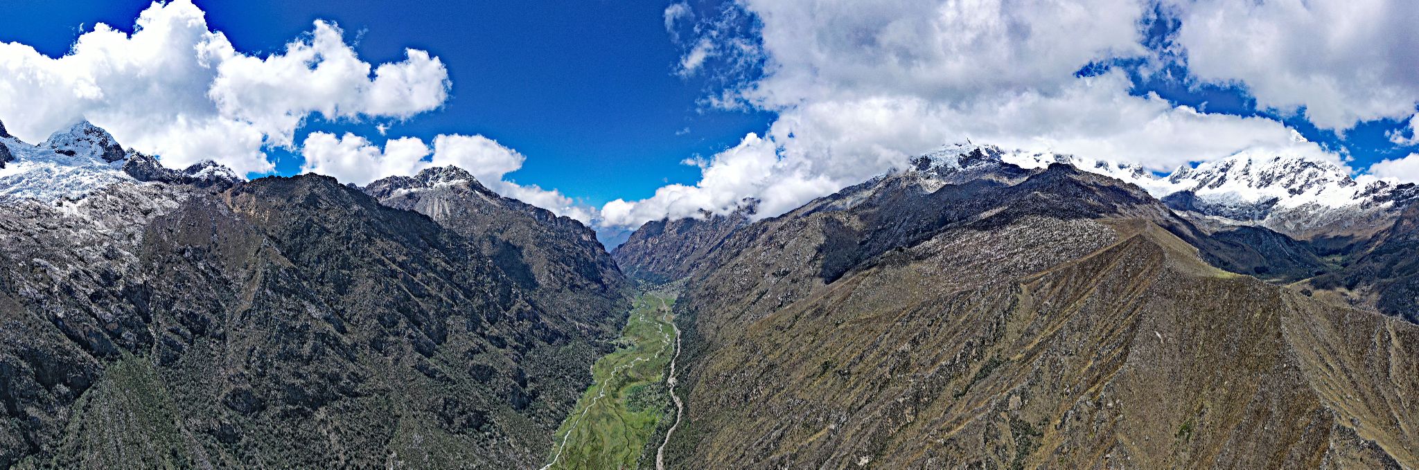 aerial view shows panoramic views of narrow valley tucked between two giant mountain sides