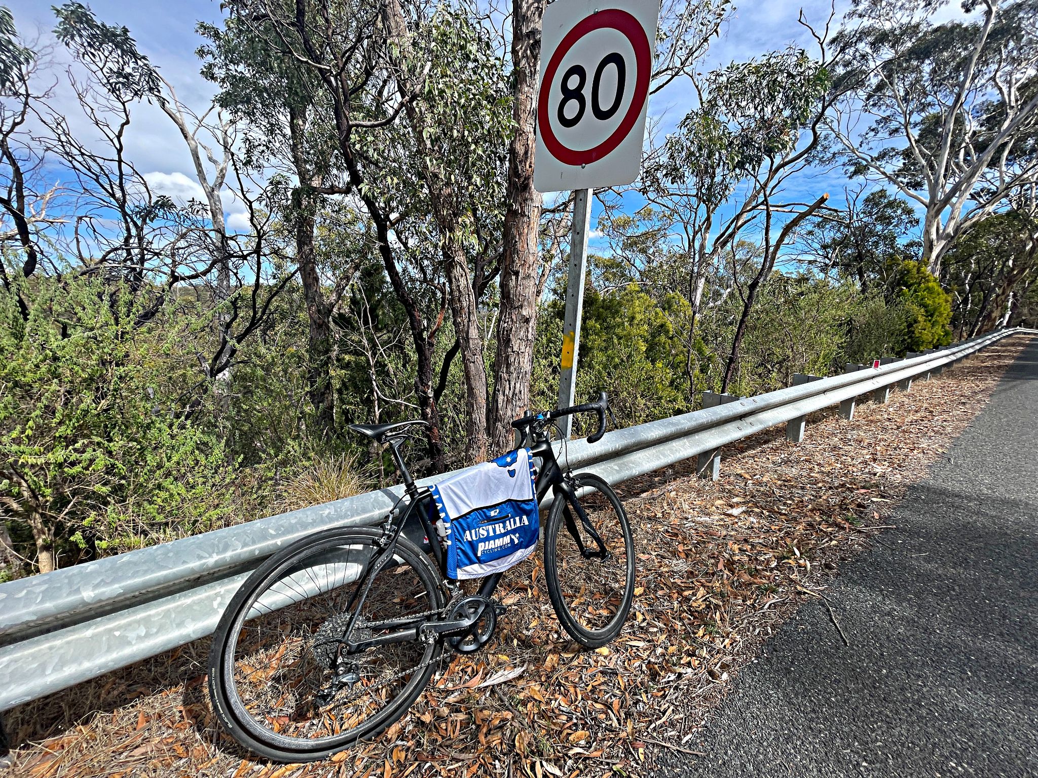 bike parked against guardrail at climb finish next to sign for 80 kph