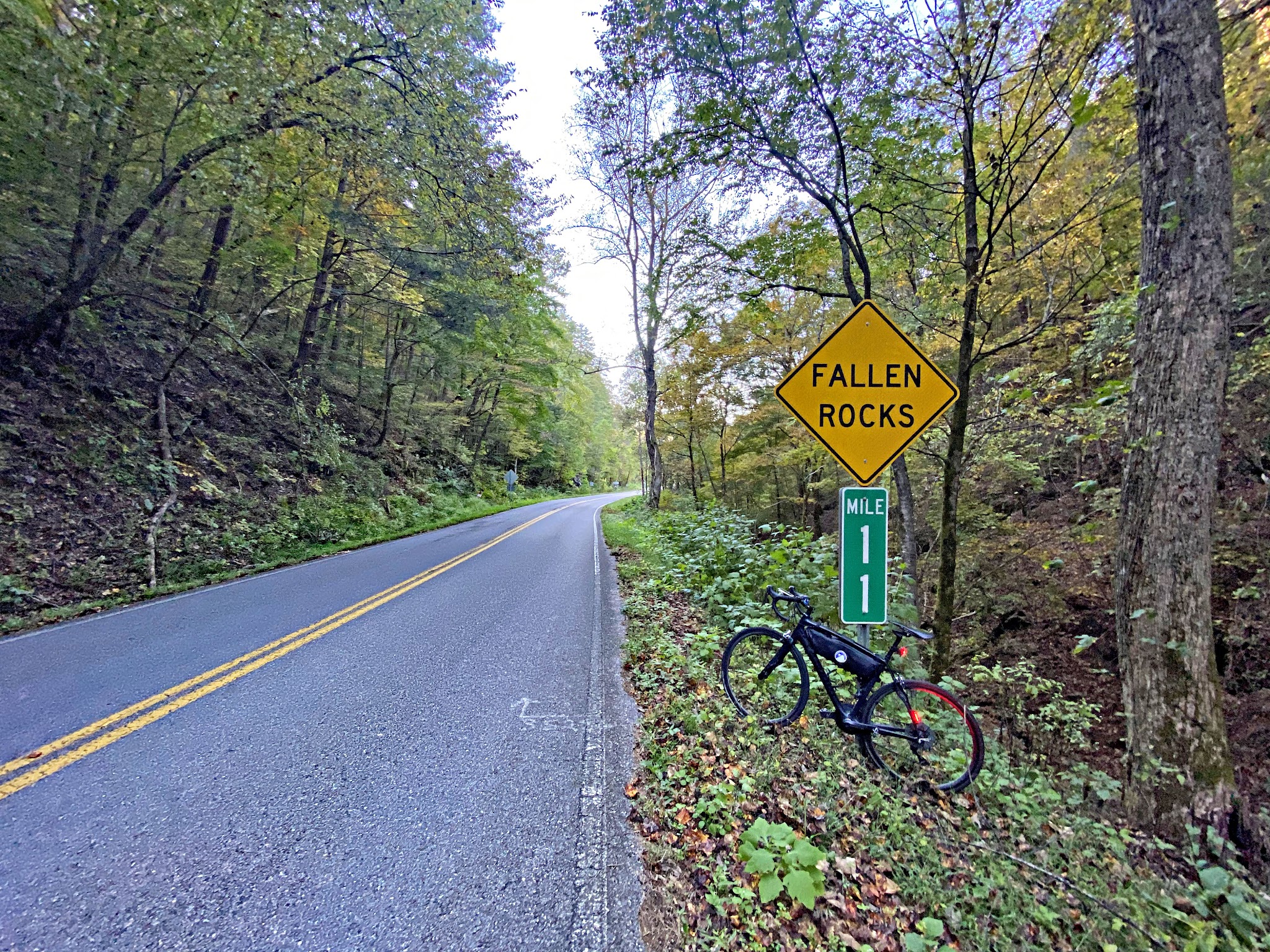 Cycling Tail of the Dragon, Tennessee - bike parked at sign for mile marker 11, sign reads "Fallen Rocks"