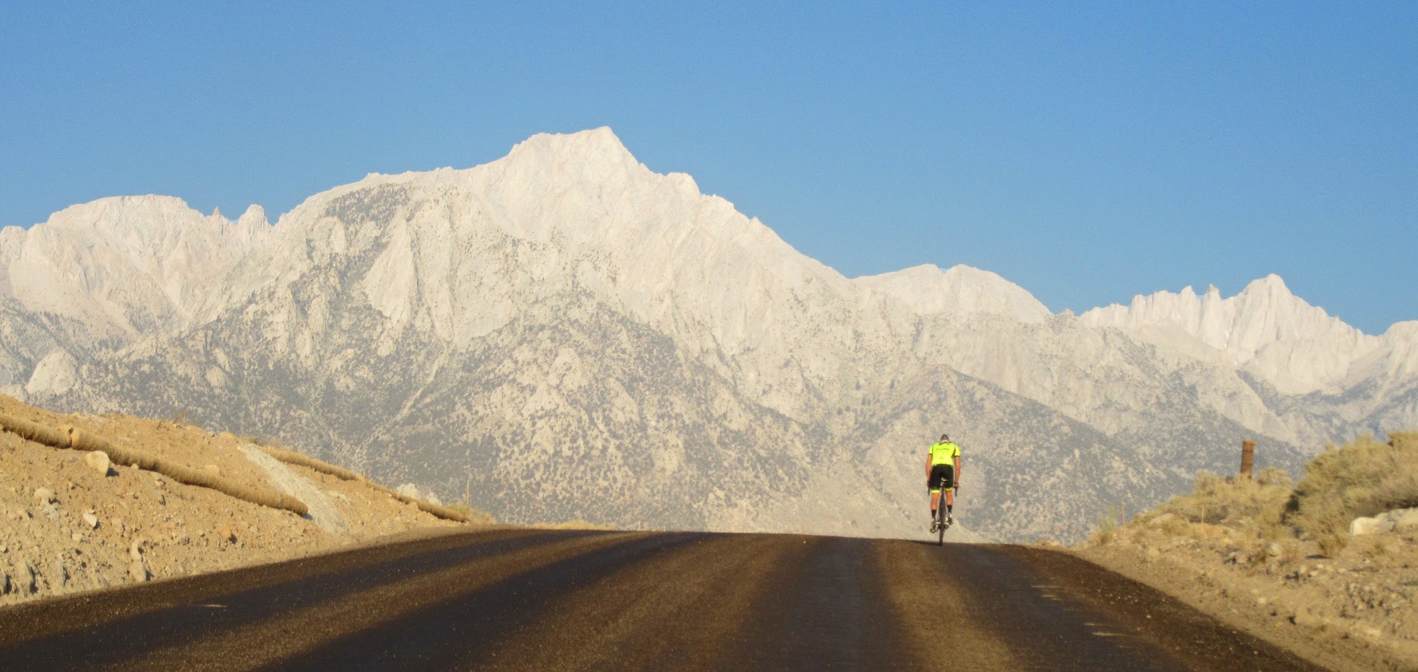 Cyclist on Whitney Portal Road with Mt. Whitney summit in background.