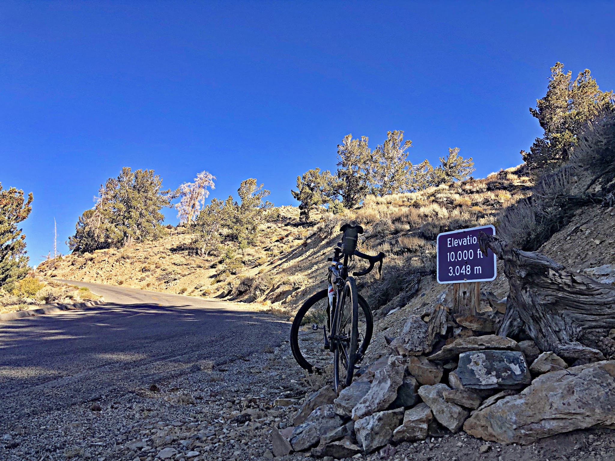 Climbing White Mountain Road by bike - 10,000' elevation sign, road, clouds