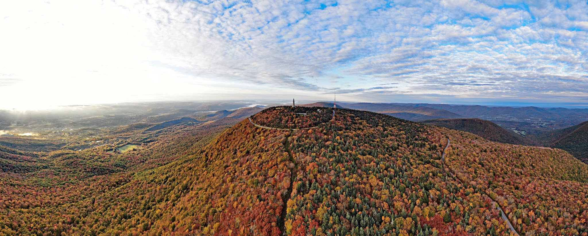 Cycling Mt. Greylock South, Massachusetts  - aerial drone view of Mt. Greylock during fall, bright New England Fall Foliage, Appalachian Trail in middle and Rockwell Road on right
