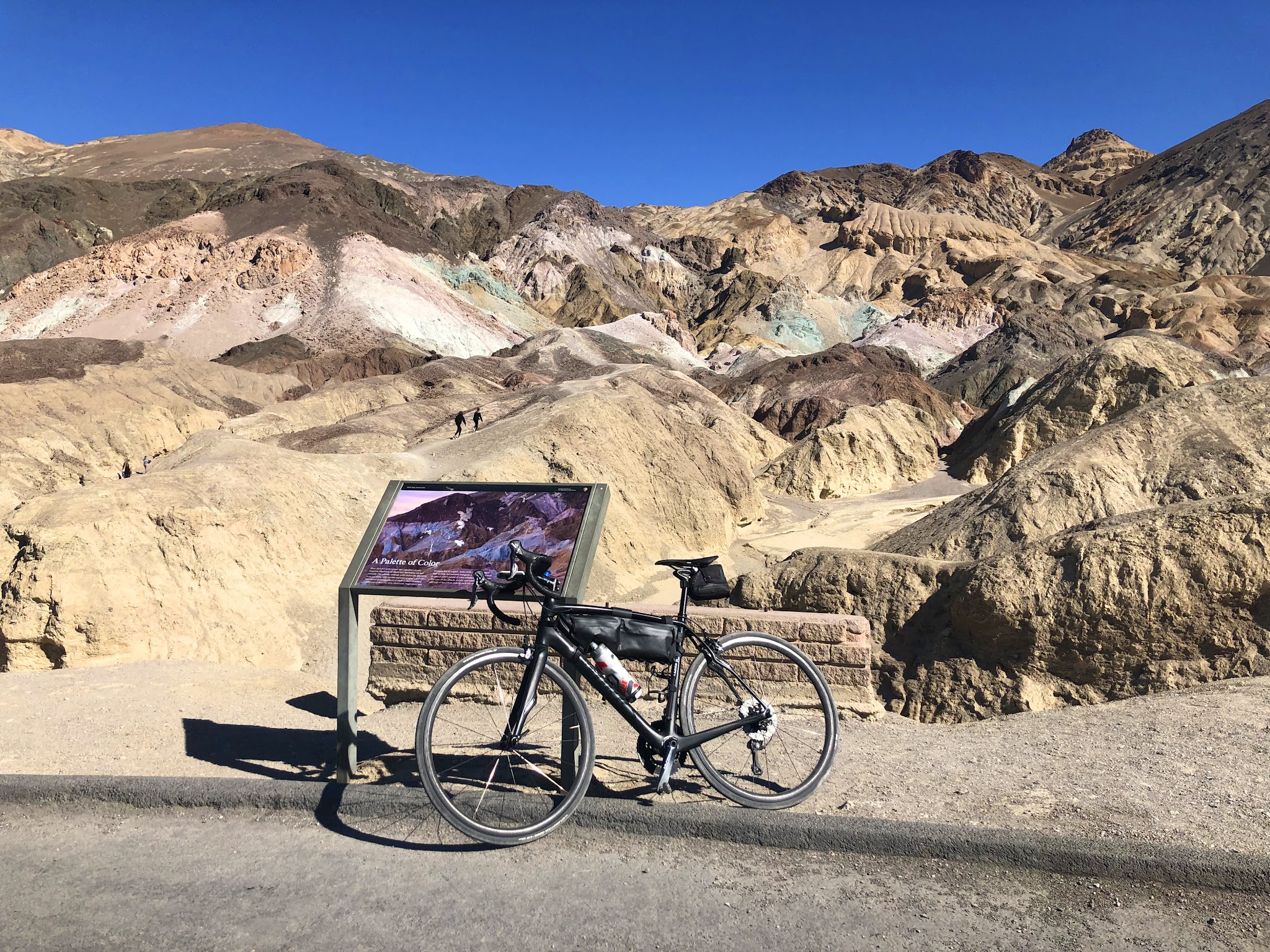 Cycling Death Valley National Park, California Cycling Death Valley National Park, California - bike parked against informational sign at Artist Drive, sandstone hills and rocks painted bright colors
