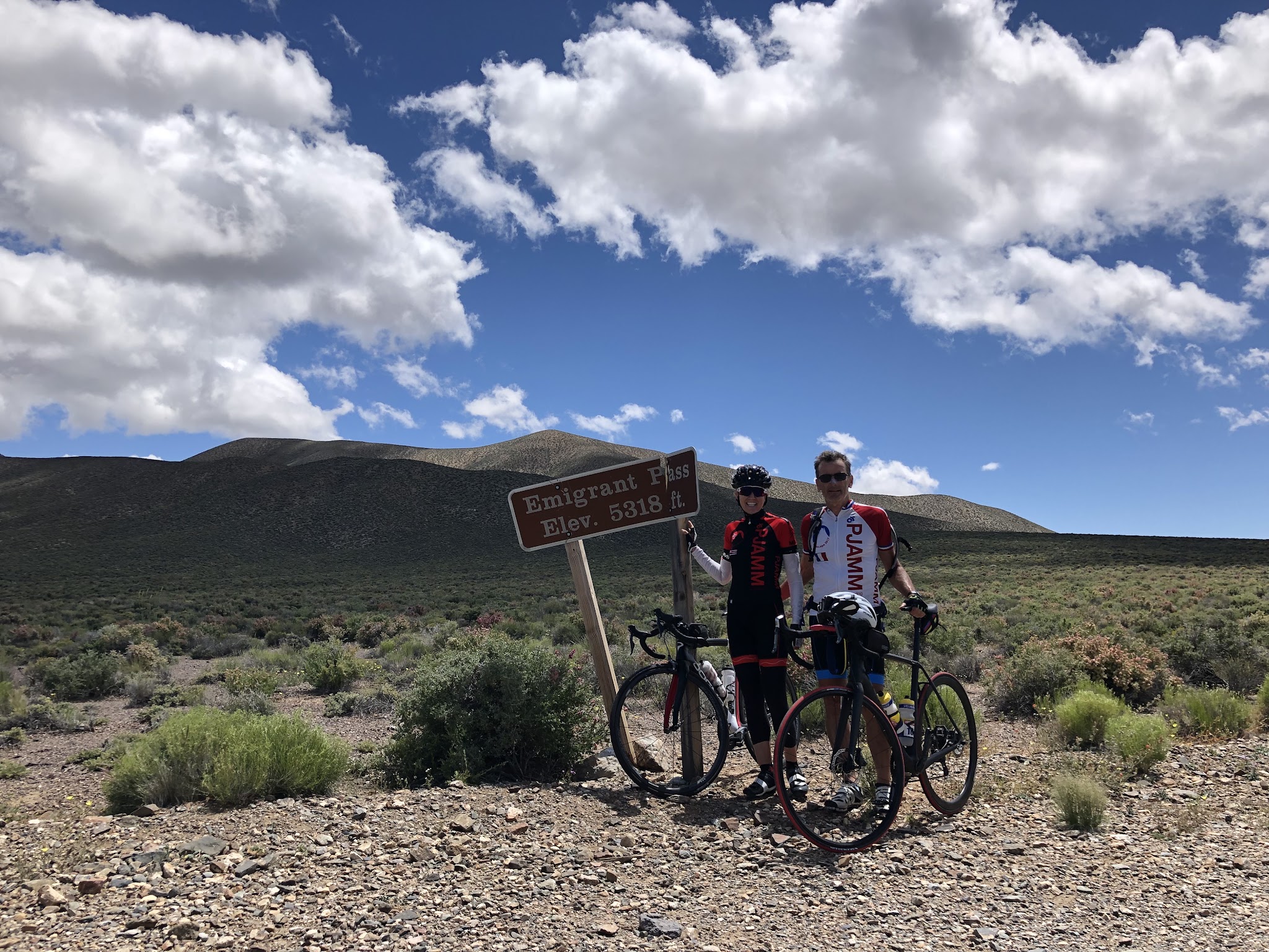 Cycling Death Valley National Park, California Cycling Death Valley National Park, California - two PJAMM Cyclists stand with their bikes next to sign for Emigrant Pass