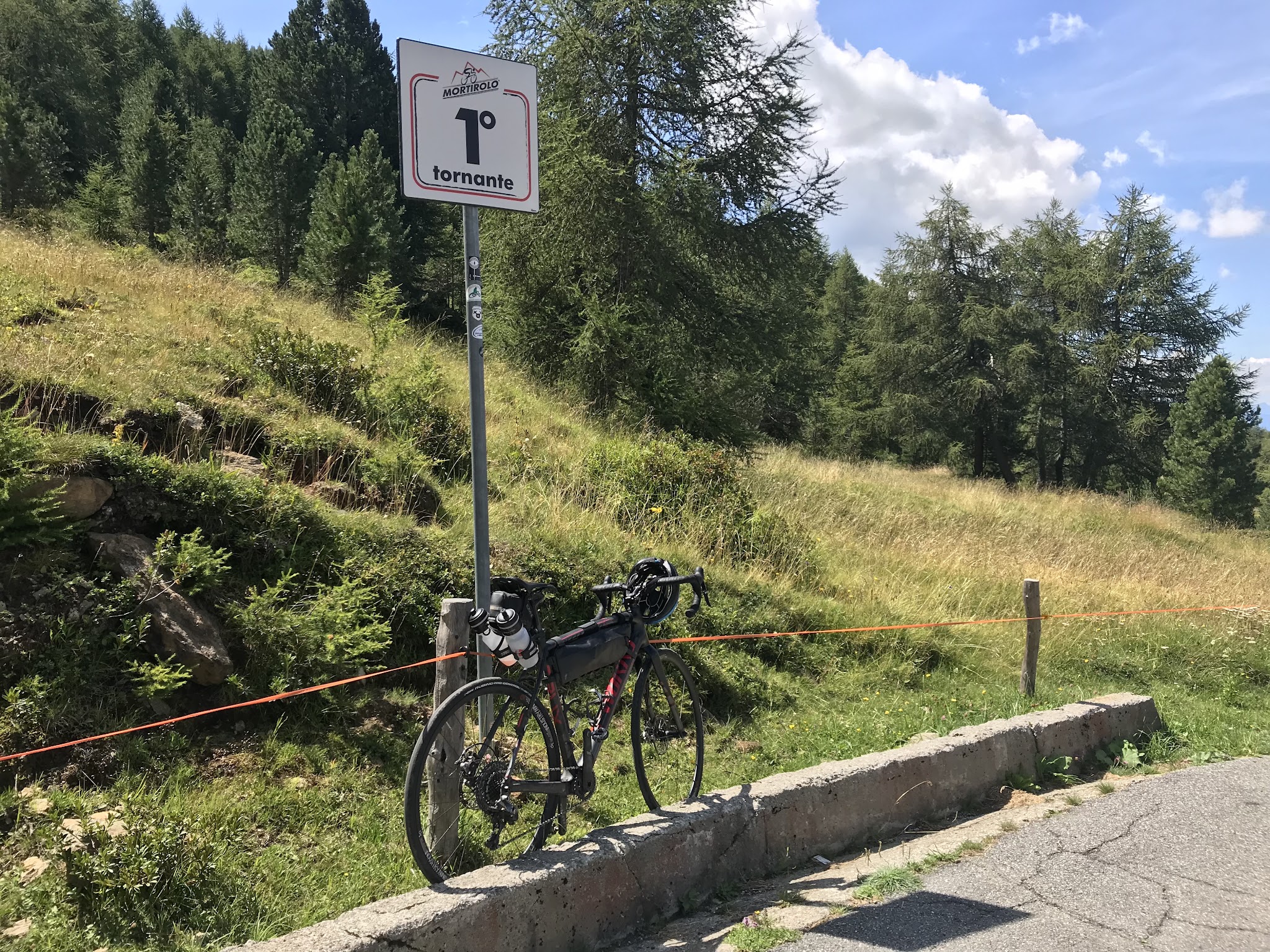 Passo del Mortirolo from Tovo - bike leaning against tornanti 1 sign.