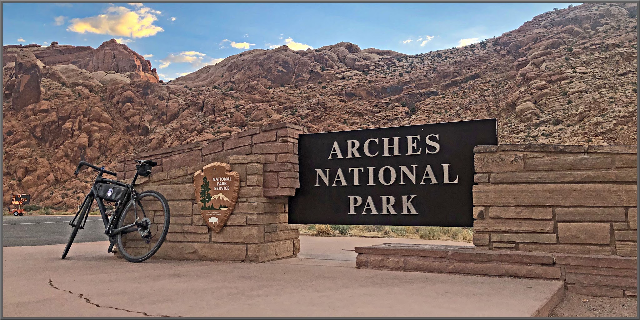 Cycling Arches National Park, Moab, Utah - bike parked in front of NPS sign for Arches National Park