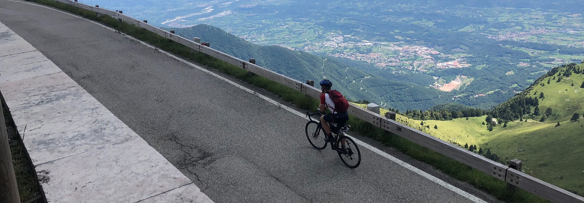 Monte Grappa - Cavaso del Tomba by bike - cyclist riding on road with plains below