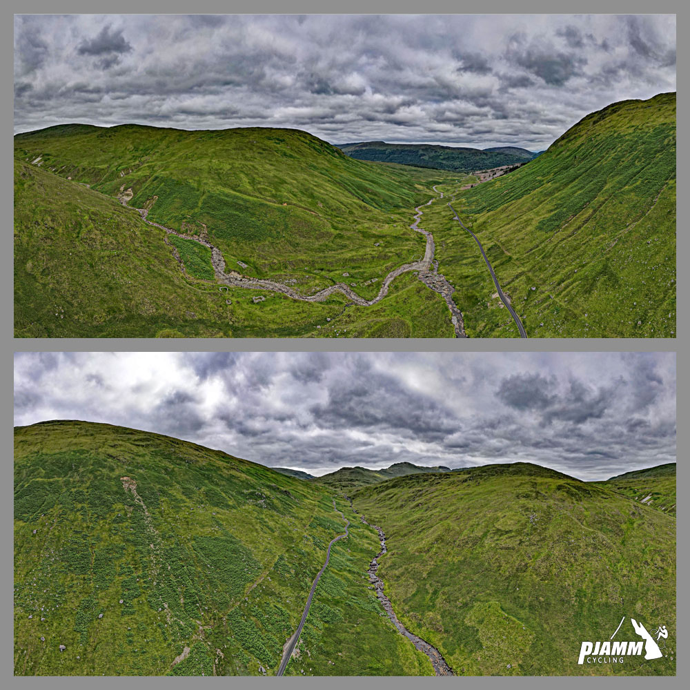 Aerial drone view shows road cutting through center of gorge, surrounded by green hillsides